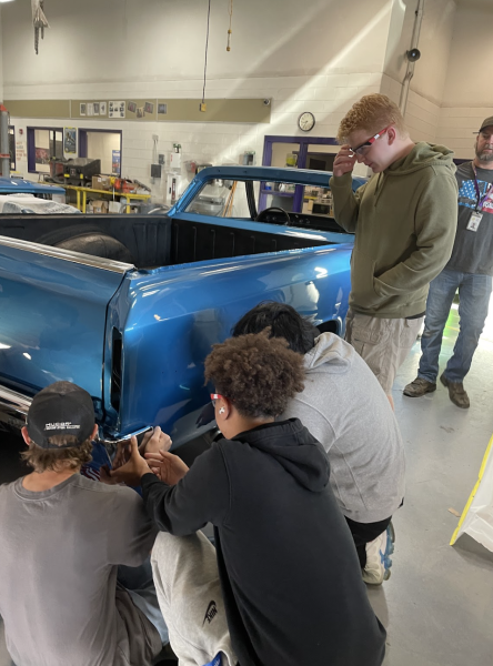 Juniors Corbin Reynolds, Kevin Buenoventura, and Grant Bacon work on a pick up truck in the auto body garage.